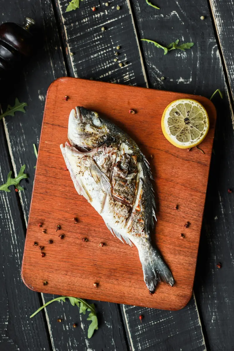 Hel grillad fisk på skärbräda